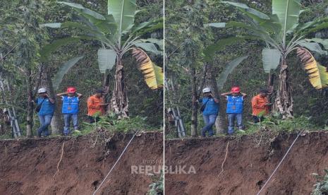 Petugas memeriksa tebing longsor di tepi jurang dekat permukiman