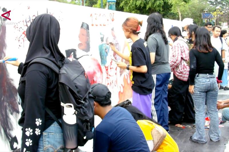 Sejumlah perempuan melukis bersama pada dinding putih dalam aksi simpatik peduli kebakaran hutan dan lahan