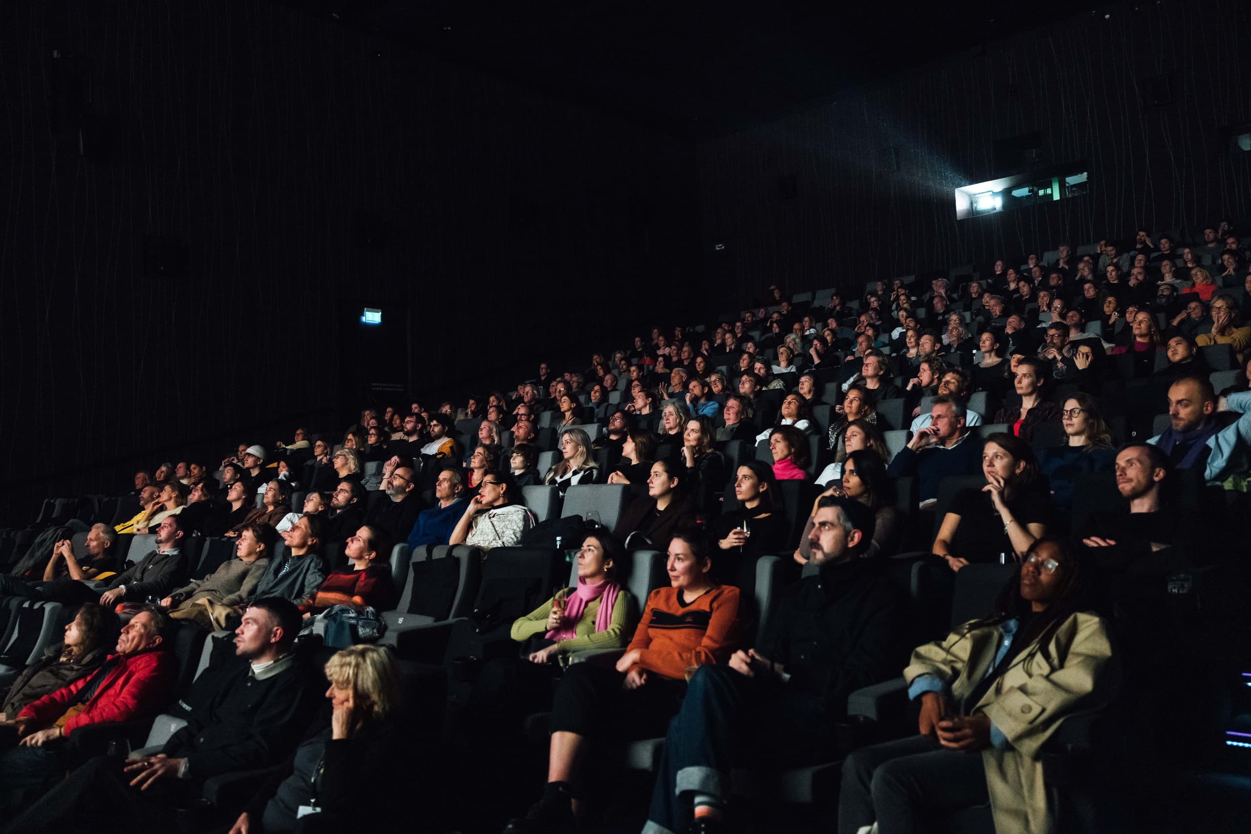 Penonton di bioskop saat festival film, suasana gelap dengan layar menyala