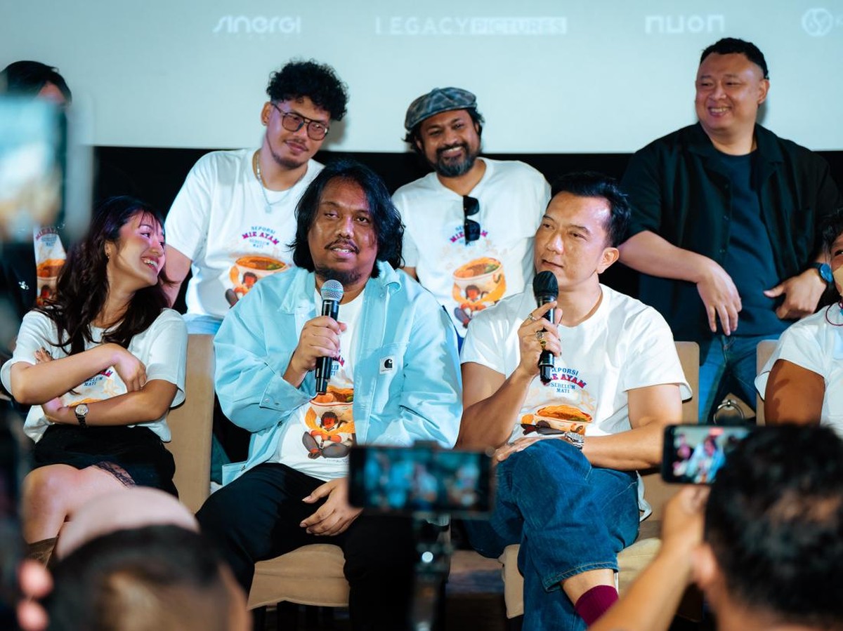 Para pemain dan kru film Seporsi Mie Ayam Sebelum Mati berkaus putih bergambar mie ayam, dua pria memegang mikrofon saat sesi bincang