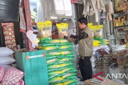 Seorang petugas memeriksa tumpukan karung beras di gudang distribusi