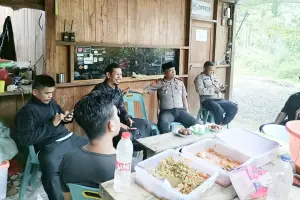 Sejumlah polisi dan warga duduk bersama sambil minum kopi di warung kayu sederhana