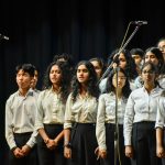 Sekelompok mahasiswa tampil bernyanyi di atas panggung dengan mikrofon di depan mereka