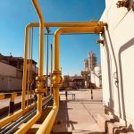 Pipa gas industri berwarna kuning dengan latar langit biru
