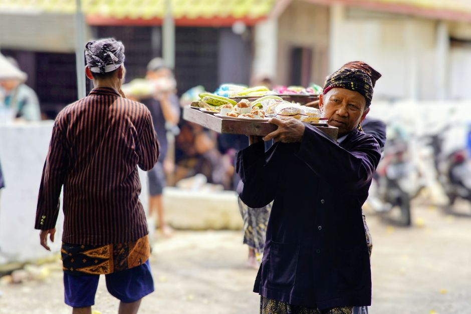 Pedagang kaki lima Indonesia membawa nampan jajanan di pasar tradisional
