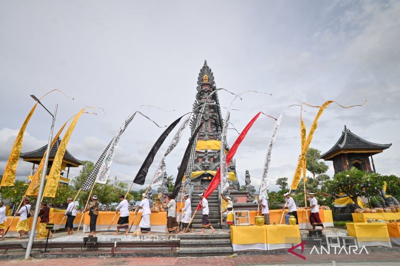 Umat Hindu berpakaian adat berjalan mengelilingi candi dalam ritual di halaman pura dengan umbul-umbul warna-warni