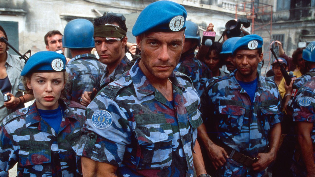 Jean-Claude Van Damme di tengah bersama para pemeran berseragam kamuflase dan baret biru dalam adegan film Street Fighter 1994