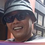 Komedian Sule tersenyum memakai topi dan kacamata hitam di luar ruangan