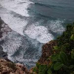 Ombak besar menghantam tebing pantai berbatu di Bali