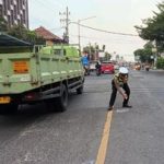 Seorang petugas polisi melakukan olah tempat kejadian perkara di jalan raya
