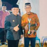 Seorang pria berbaju batik memegang piala sambil mengacungkan jempol pada malam penganugerahan MTQ