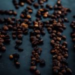 Biji kopi sangrai dari dekat yang tersebar di atas permukaan gelap, menampakkan tekstur dan warnanya
